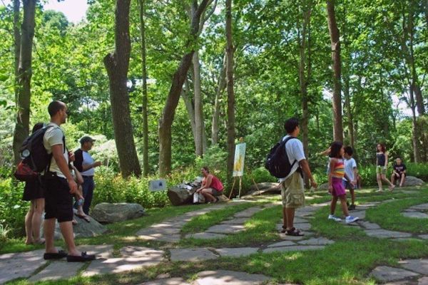 Numerous adults and children stand in and walk along the stone path in a labyrinth.