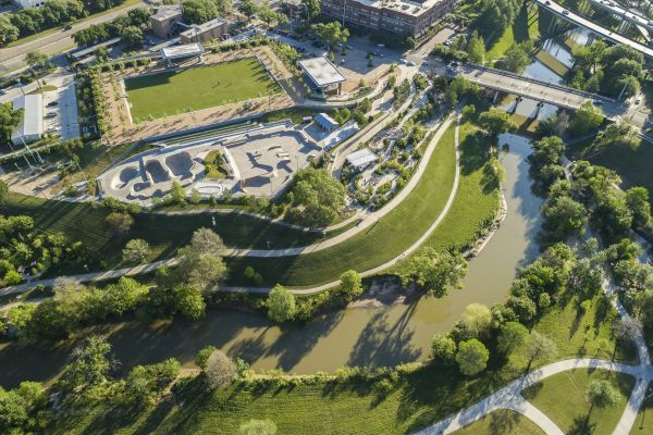Aerial view shows the meandering Buffalo Bayou waterway, grassy banks, and paved walkways.