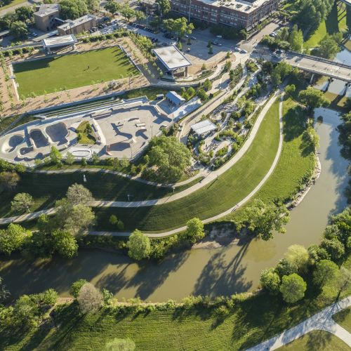 Aerial view shows the meandering Buffalo Bayou waterway, grassy banks, and paved walkways.