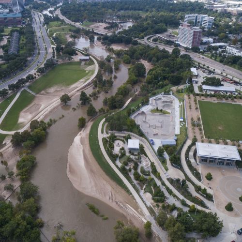 An aerial view shows a flooded waterway with trees partially submerged. 
