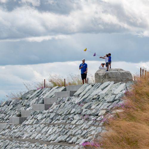 Children and adults on man-made hill with Puget Sound in background
