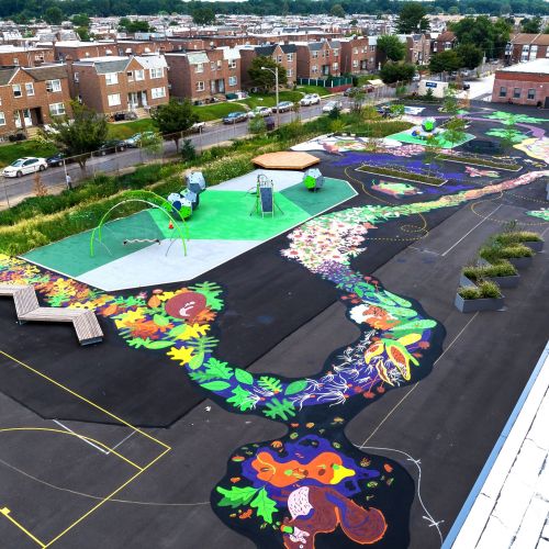 An aerial image of the playground showing play equipment, gathering spaces, and a painted ground mural looping around the playground. 