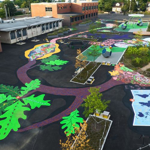 An aerial view of the playground showing brightly colored painted pathways and features including leaves, insects, and maps to support student ecological learning. 