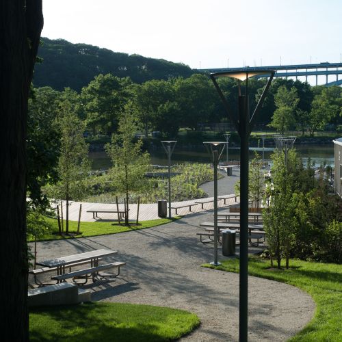 A curved path winds between picnic tables, grassy areas, and buildings.