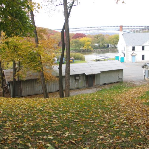 Several buildings and a grassy hillside with fallen leaves.