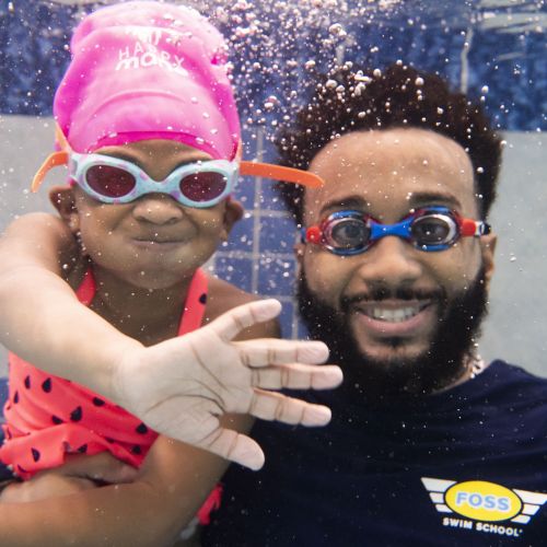 A Making Waves child and adult smile underwater wearing goggles 