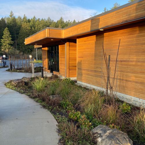 Natural-looking landscaped beds and curving walkways with a wood-sided building on the right.