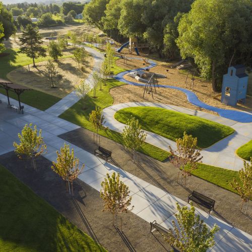 Aerial photo shows well-maintained paths, grassy mounds, a playground, and trees.