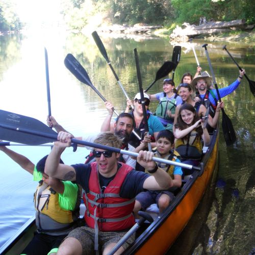 A group poses with their oars raised up in joy during a canoeing outing in 2015. 