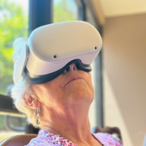 A participant wearing a white VR headset tilts her head up as she concentrates on the VR experience.