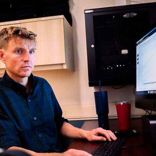 A VRN member sitting at a computer focuses on editing 360-degree videos into VR experiences for participants to enjoy.