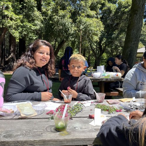 Participants sit at an outdoor table using plant-based dyes to make art, an activity enjoyed during a Family Camp event.