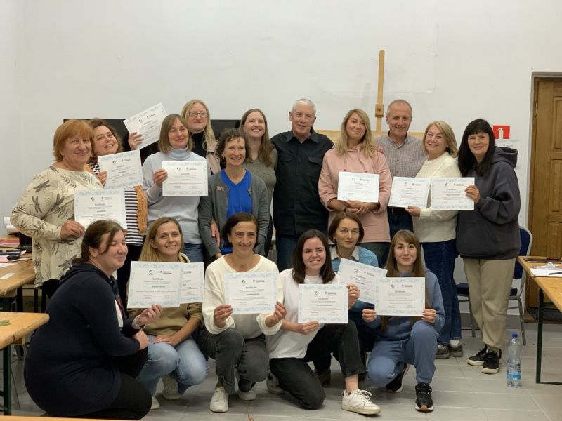 A group of people standing and kneeling, smiling at the camera while holding large certificates.